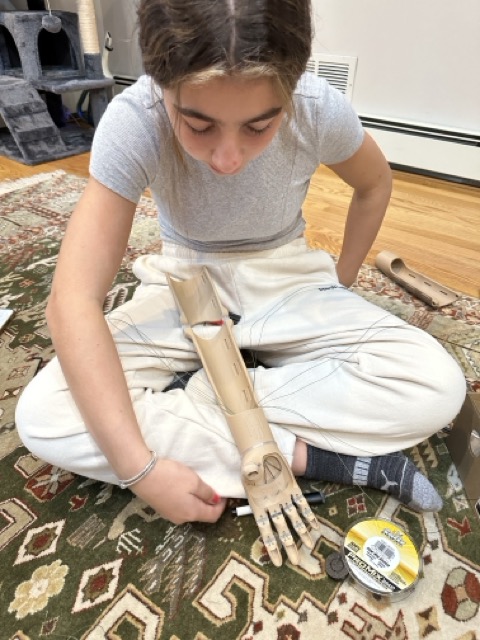 Laila assembling the arm, tensioner cords threaded by hand