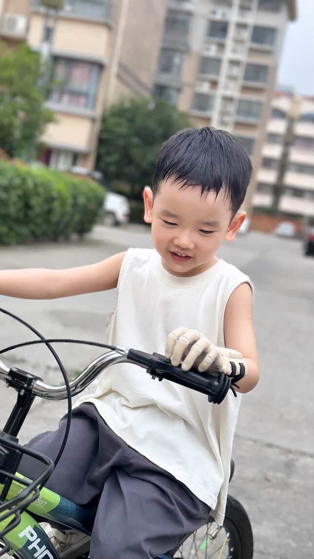 W. smiling on his bicycle, prosthetic hand on the handlebar