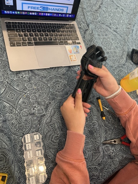 Laila assembling the arm, Free3DHands reference open on laptop
