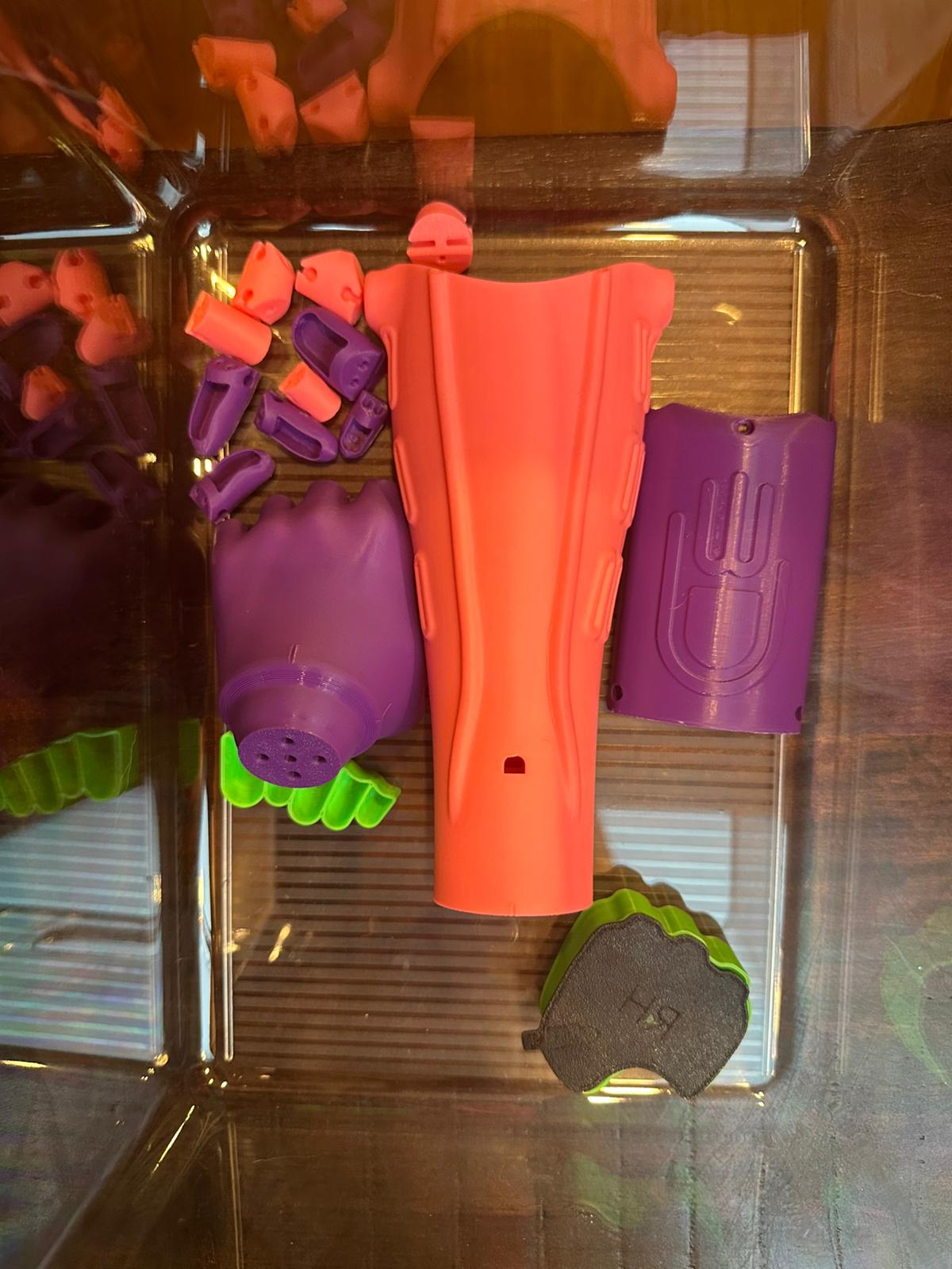 All printed components laid out in a tray — coral, purple, and teal parts