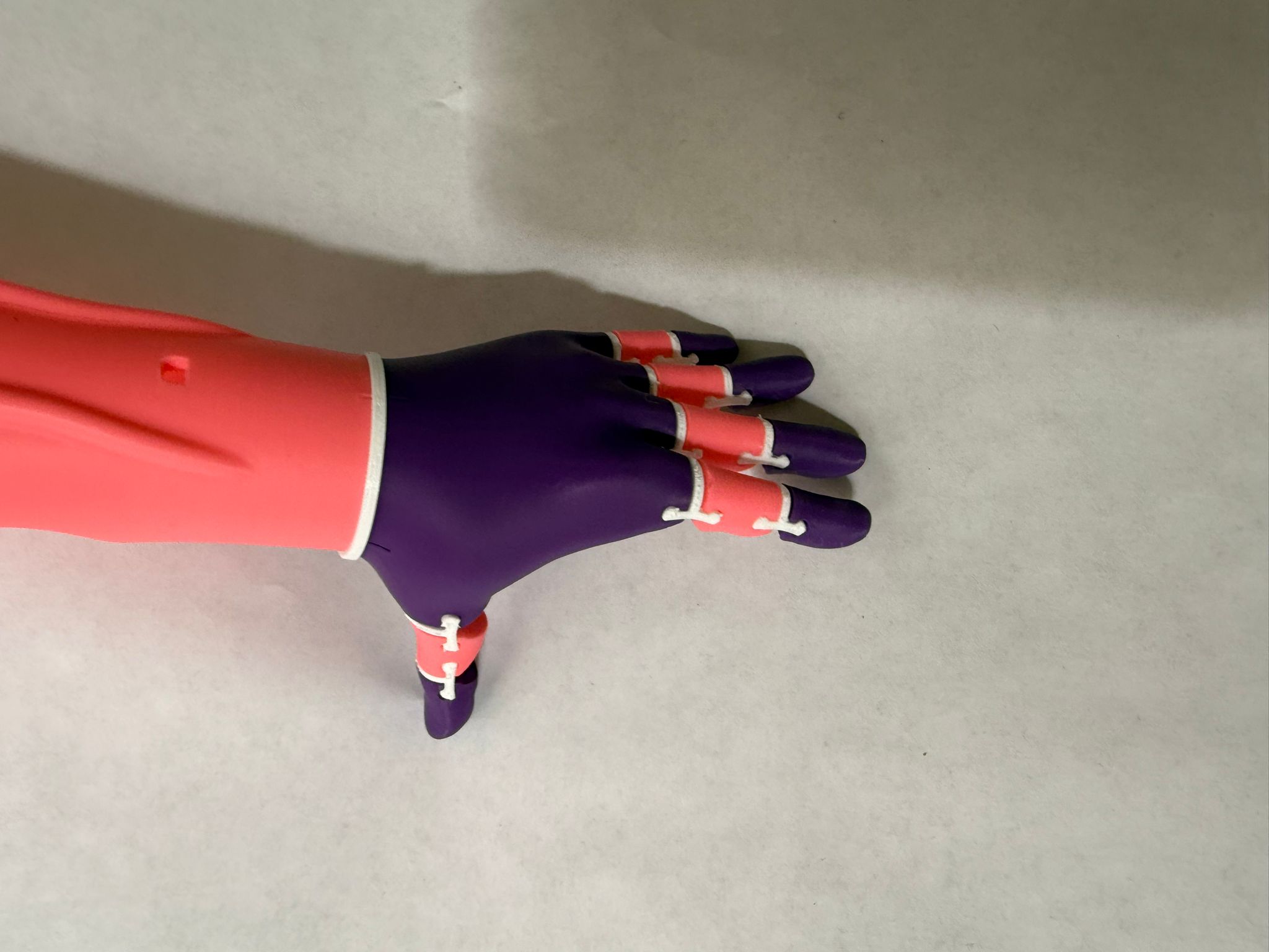 Completed arm laid flat showing open-hand position — purple fingers, coral forearm