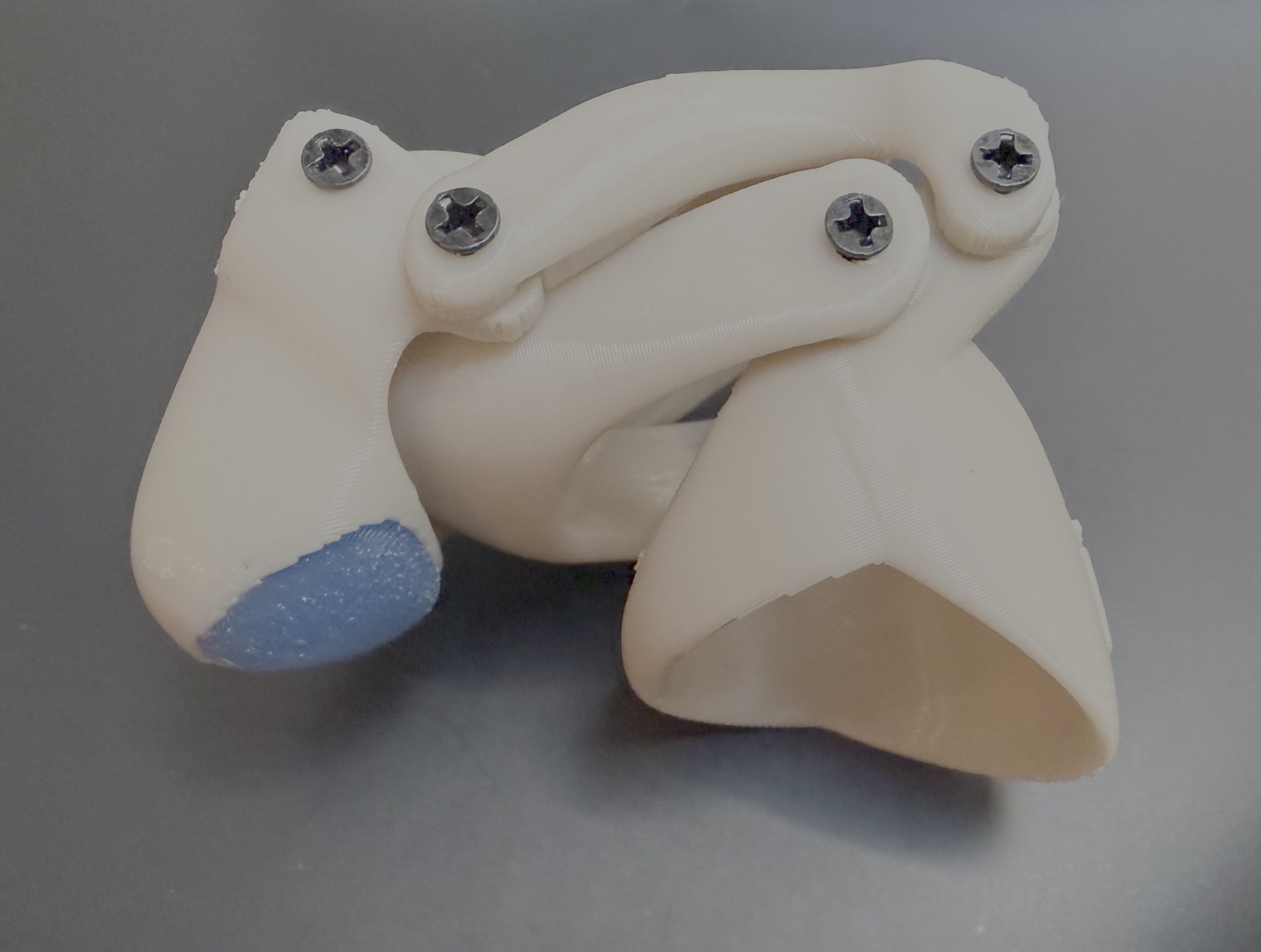 Finished Gravity CAD prosthetic in the bent/closed position, blue silicone fingertip and screws visible, studio shot on gray background