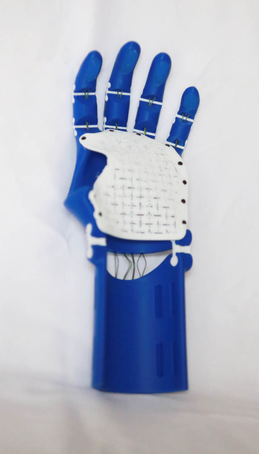 The finished 65% dark blue Thumbless Kinetic Hand standing upright on white fabric, showing the palm plate and blue fingers
