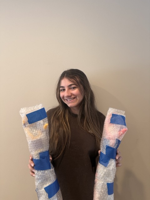 Laila smiling, holding both bubble-wrapped arms ready to ship to Abuja, February 2026