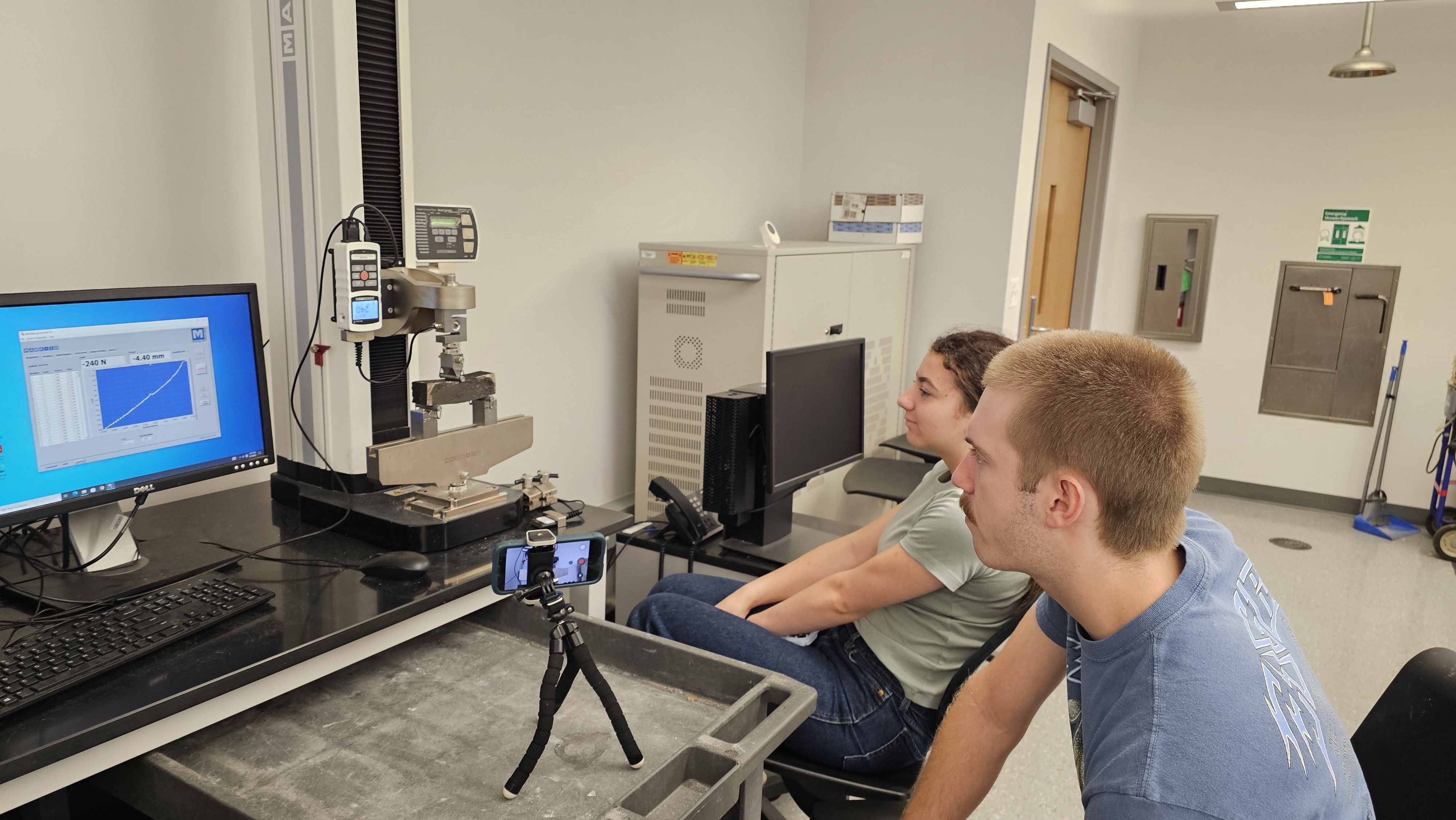 Laila and a graduate student watching the load curve on a materials stress-testing machine at LSU