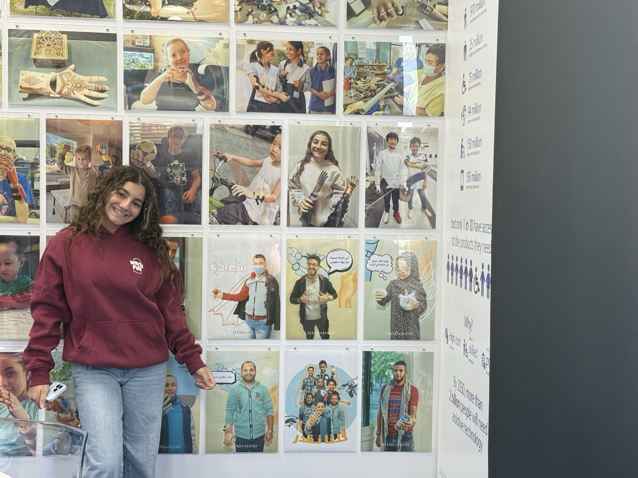 Laila at Free3DHands headquarters in Australia, beside a wall of her completed prosthetic cases
