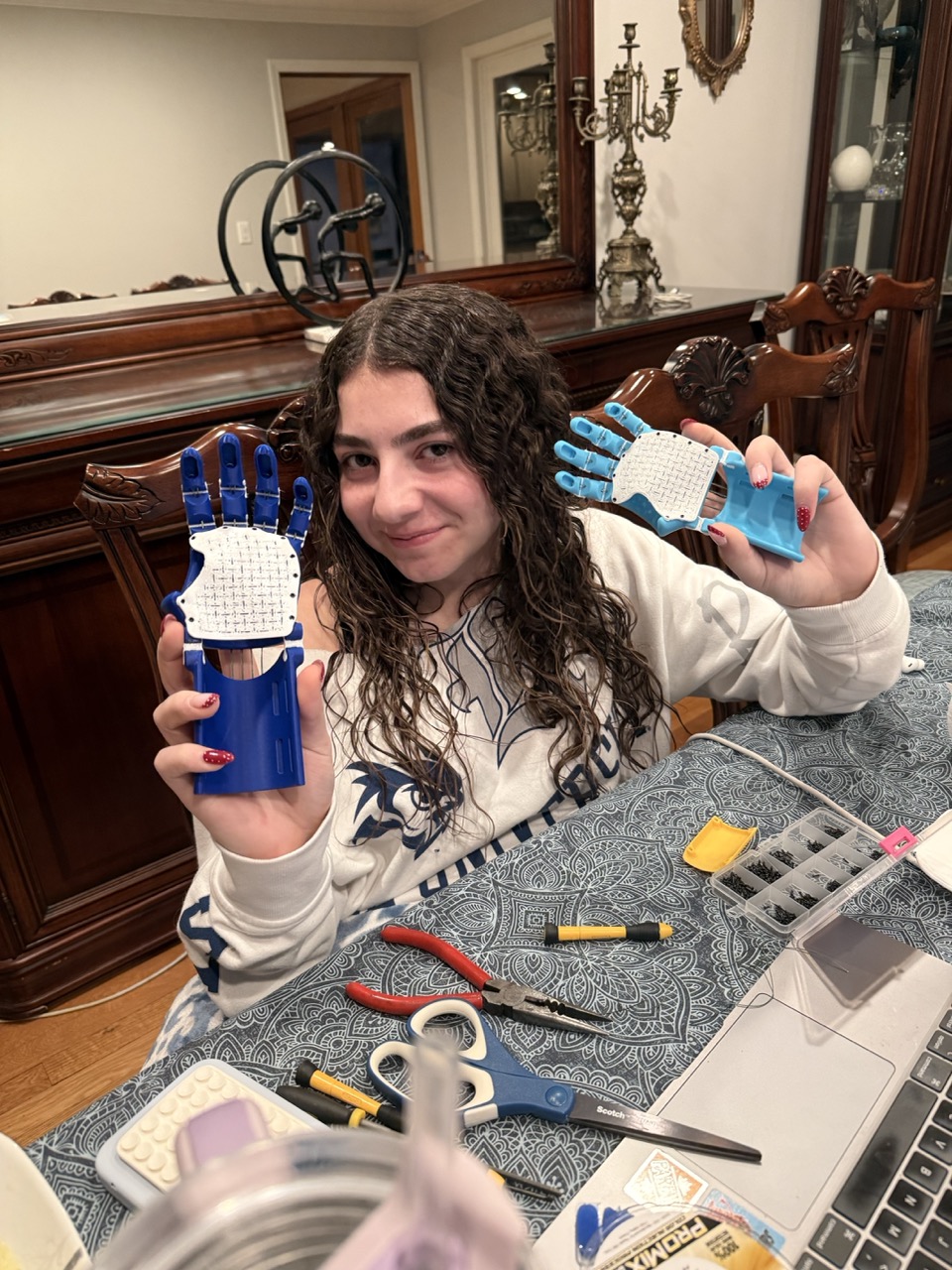 Laila at her workshop table assembling prosthetic arms